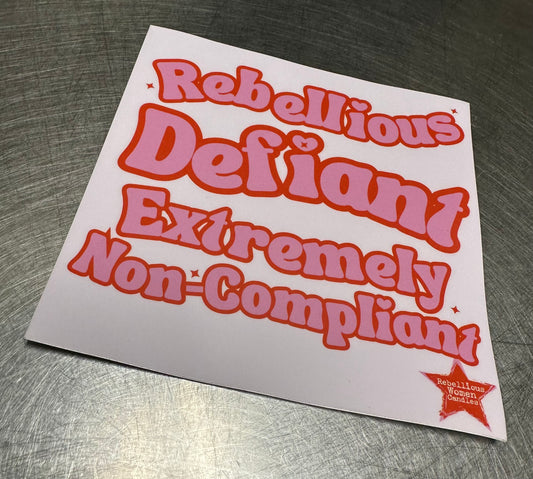 Sticker with text 'Rebellious Defiant Extremely Non-Compliant' on a metallic surface